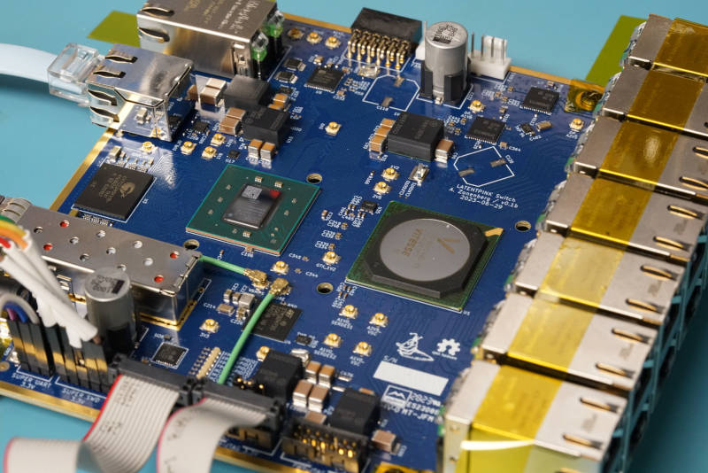Blue PCB with a row of RJ45 connectors at the front, a SFP+ cage out the back, and several large BGAs in the middle