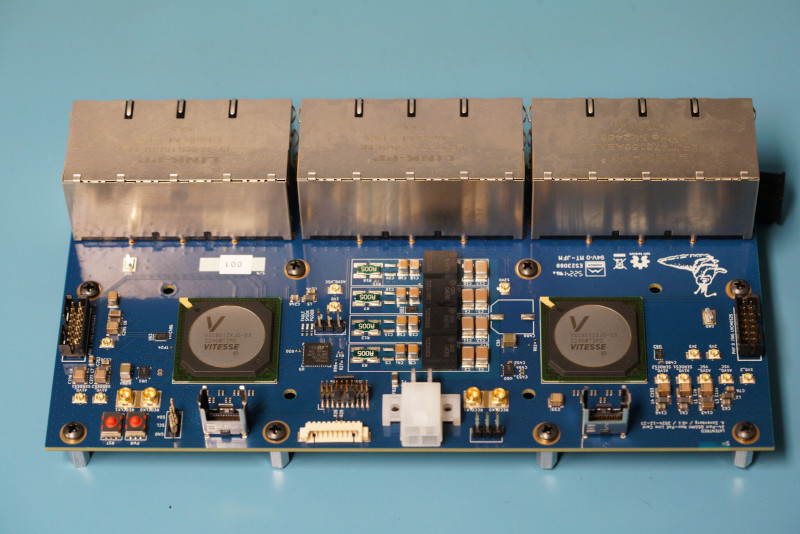Blue PCB with three 8-port RJ45s and two large BGA PHYs,