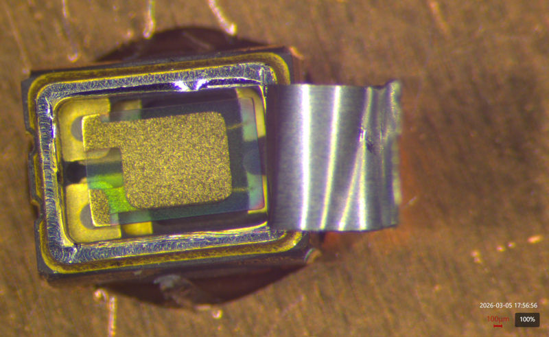 TCXO package with lid almost fully peeled off hanging by one side